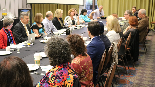 A large group of people meet around a conference table.