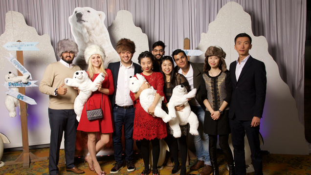 A large group of students stand in front of polar bear and white mountain decorations.