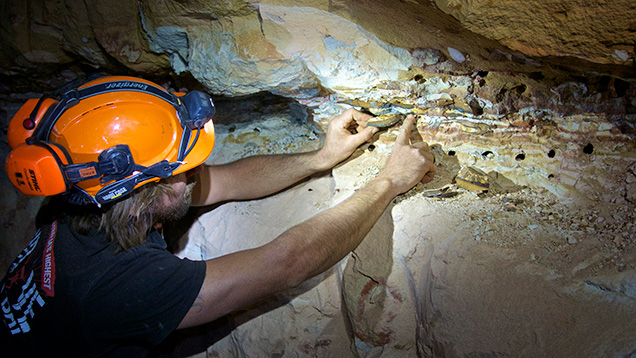 Man pointing to opal vein in underground mine