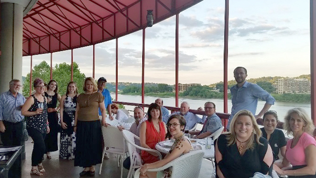 A group of people in a restaurant setting – overlooking the water.
