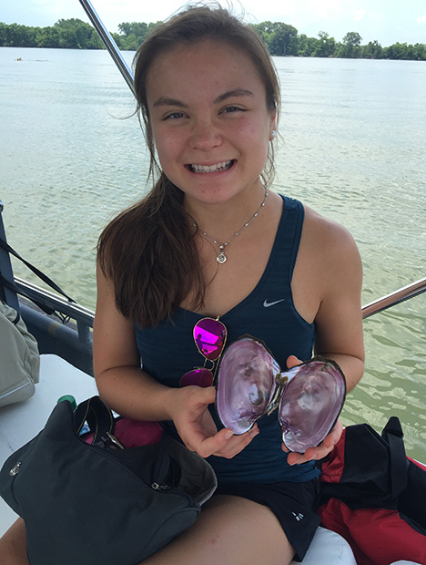 Young girl holding an open pink mussel shell