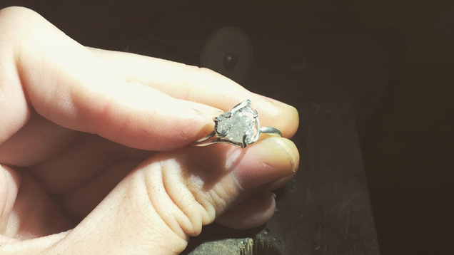 ダイヤモンドの原石を特徴とするリングを手にするGrandicsの指のクローズアップ。