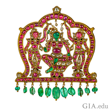 Gold pendant featuring carved drawings of indian gods and emeralds and rubies