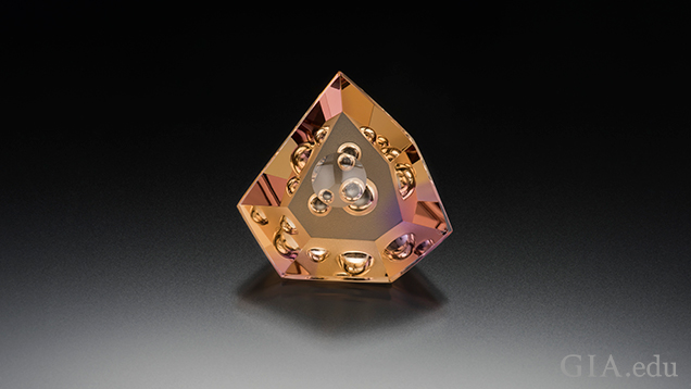 A triangular shaped piece of ametrine (yellow and purple) with “bubbles” of internal carvings.