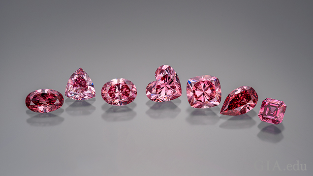 A row of various shaped cut and polished pink diamonds.