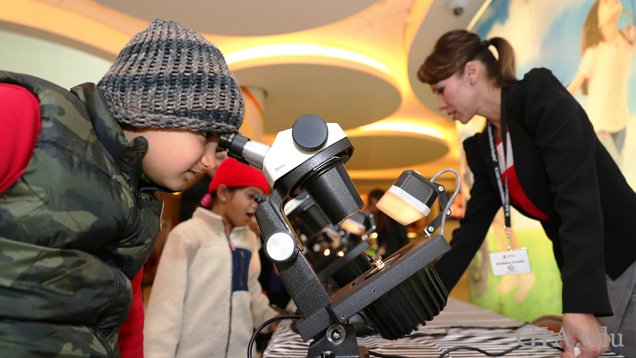 A young boy looks through a microscope.