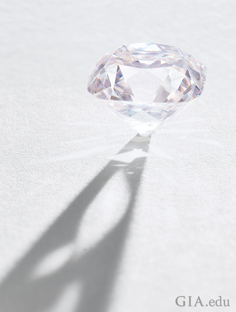 An unmounted light pink diamond stands on its culet.