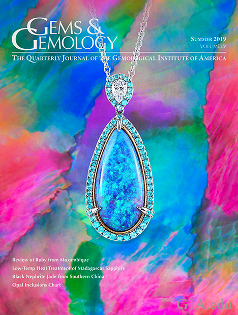 A black opal pendant, accented by pear-shaped diamonds and round Paraíba tourmalines, sits on a photomicrograph of a black opal from Lightning Ridge, Australia, that shows broad, angular flashes of play-of-color known as a harlequin or mosaic pattern.