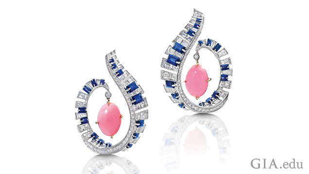 The frames of the earrings are designed a scroll from which a pink conch pearl dangles. The scrolls are comprised of blue sapphires and diamonds to look like piano keys.