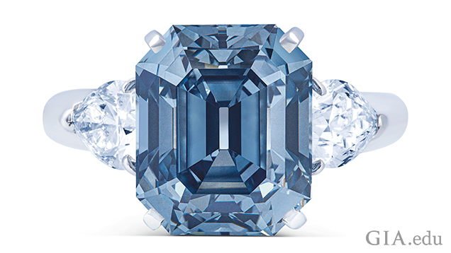 A rectangular cut Fancy Deep blue diamond is framed by two pear shaped diamonds.