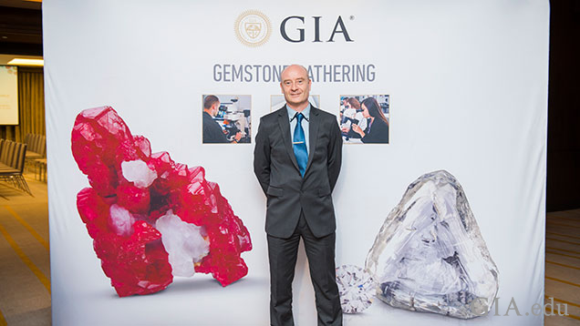 Man stands in front a GIA banner that features gemstones.