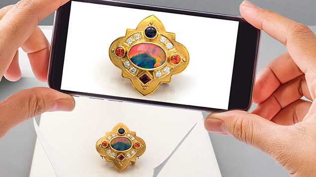 Image of smartphone camera taking a photo of a gold brooch with gems