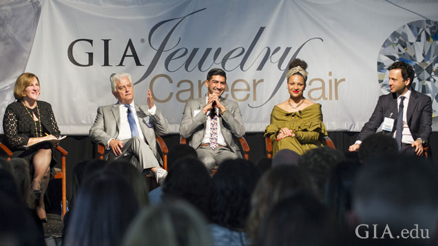 Moderator and four panelist sit smiling as they answer audience questions