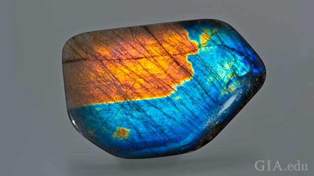 This predominately blue gem has a large orange area in the top left and patches of green and orange elsewhere.