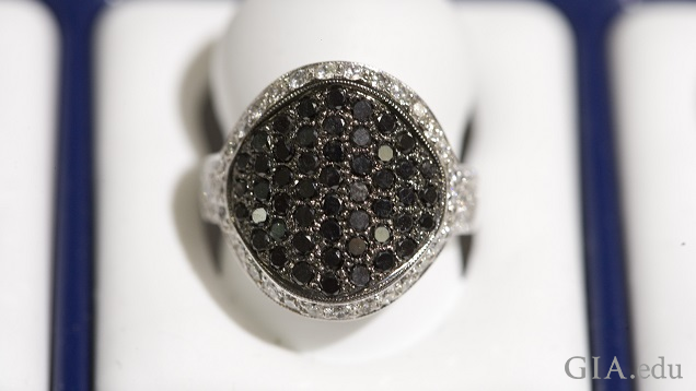 The large center of the ring is comprised of multiple black diamonds and is framed by a row of colorless diamonds.