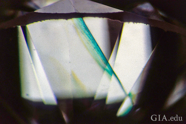 This cleavage crack shows a bright green “flash effect” when observed subparallel to the plane of the break against a bright background. This is diagnostic of clarity enhancement in diamonds. Field of view 3.20 mm.