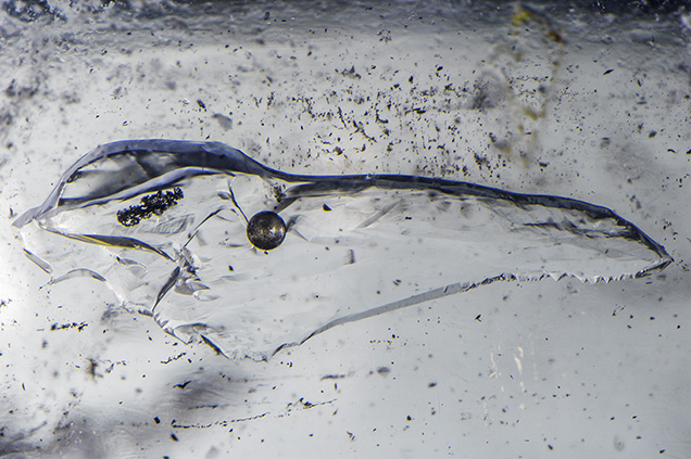 Silver-gray gas bubble floats in a liquid-filled void.