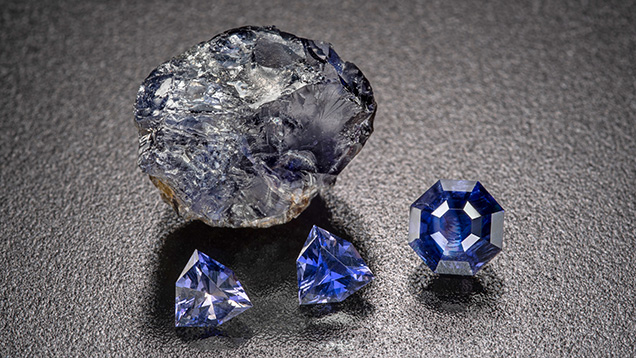 Figure 11. Rough and cut iolite from the Blue Arrow occurrence. The faceted stones weigh up to 1.15 ct, with the two matching triangular stones weighing approximately 0.8 ct in total. Photo by Michael Bainbridge.