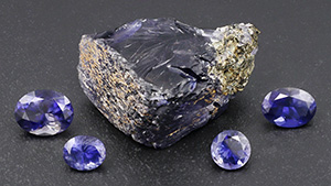 Figure 12. Rough and cut iolite from Blue Bear. From left to right, the faceted stones weigh 1.24, 0.48, 0.48, and 0.88 ct. Photo by Philippe Belley.