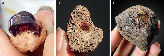 Figure 2. Basalt-hosted gem materials from southeast Vietnam: A subhedral zircon crystal in laterite (A), a garnet xenocryst in basalt (B), and a brown peridot nodule in basalt (C). Photos by Le Ngoc Nang.