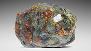 Figure 1. Mantle eclogite xenolith (2.8 cm in longest dimension) consisting of clinopyroxene (green) and garnet (red-orange), with a partially exposed octahedral diamond. Photo by Annie Haynes. Gift of Mark Mauthner, GIA Museum no. 37511.