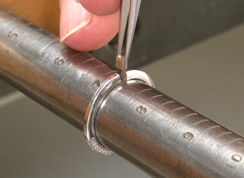 Tweezers are used to insert platinum sizing stock into a ring held on a mandrel