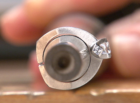 Side view of a platinum solitaire ring on a ring mandrel where gaps around the ring indicate that the ring is out of round.
