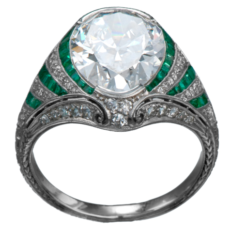 Perspective view of platinum ring with large diamond as the center stone. The shank is elaborate, with emerald baguettes alternating with channel-set round diamonds, millgrain, and other fine details.