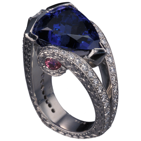 Perspective view of platinum ring with a large, trillion-cut tanzanite protected by a partial bezel as the center stone. The split shank is detailed with small gemstones, fine engraving, and millgrain.  