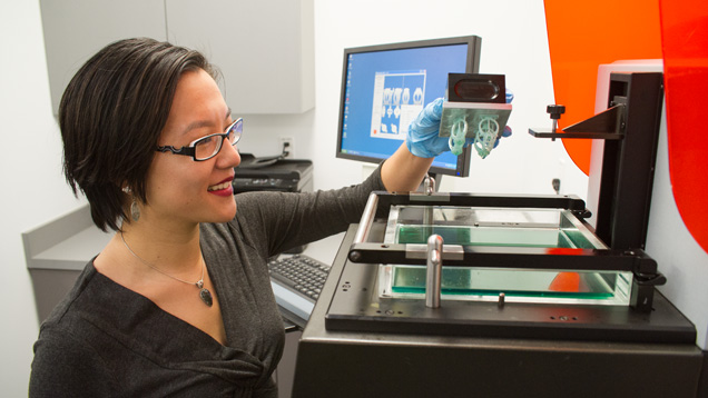 Michelle Loon removes the build platform from the 3-D printer. Photo by Kevin Schumacher