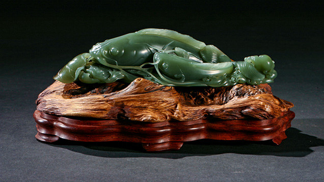 Green nephrite carving on a carved wooden base