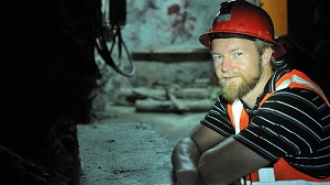 Man in a hard hat sits in an underground emerald mine.