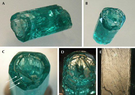 Figure 18. A and B: Sample 18 (19.6 mm in length), an emerald crystal developed in the form of a deep cup. B and C: Openings at one end are developed in the basal pinacoid but also in the largest <em>p</em> dipyramid (arrows); within the cup, a framework of irregularly shaped thin emerald walls is present. D: The crystal faces at the inner surface of the wall are oriented parallel to the outer prism faces. E: Growth steps on the surface of an <em>m</em> prism. Photos by K. Schmetzer; fields of view 11.5 mm (D, vertical) and 5.1 mm (E).