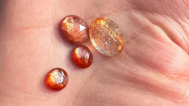 Figure 7. Sunstone with schiller from Madras, India, demonstrating the variety available in terms of depth of color and transparency. Note the bicolor nature of the larger faceted gem (13 × 17 mm), which exhibits a blue tinge at the top and bottom. Photo by Jennifer Stone-Sundberg; courtesy of Sami Gems & Jewellers.