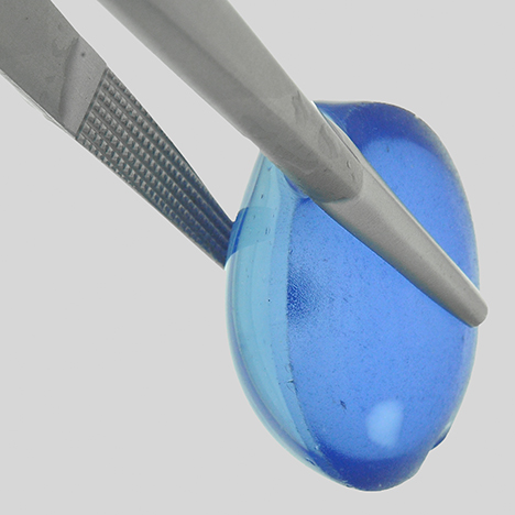 Synthetic star cabochon showing shallow coloration with a colorless circular area of repolishing.