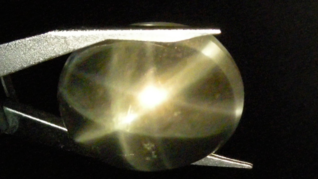 Slightly brownish pink quartz cabochon from India showing a double star in reflected light