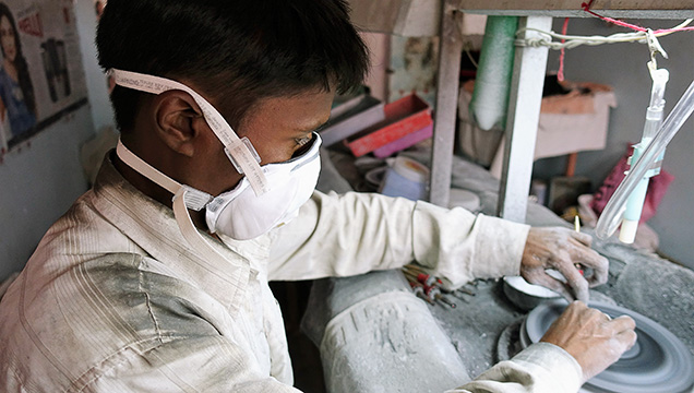Gem cutters in Jaipur wear masks provided by AGTA.