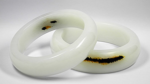 Two white jade bracelets with dark color patches.