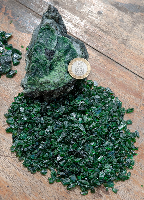 Figure 12. Nodule of tsavorite garnet from Tsavo, Kenya, within the metasedimentary host rock along with gemmy crystals obtained from similar formations. Photo by Vincent Pardieu/GIA.