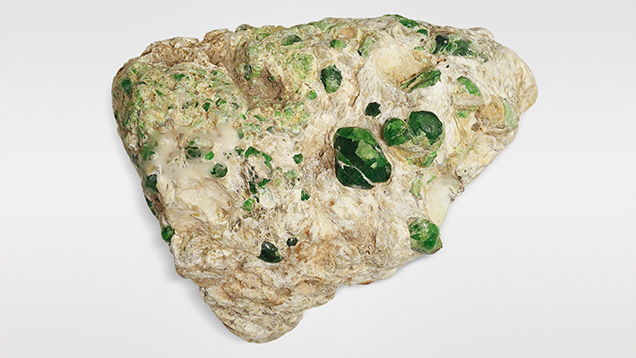 Figure 16. Nodules of demantoid garnet in a 28.87 g serpentinite rock. Photo by Aaron Palke.