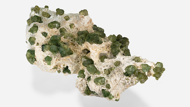 Figure 18. Skarn-hosted demantoid from Madagascar is hosted in rocks composed of typical skarn minerals such as diopside and wollastonite, among others. This specimen measures 15 × 7 × 5 cm. Photo by Orasa Weldon; courtesy of the GIA Collection.