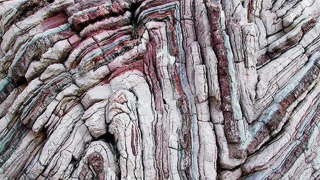 Figure 2. Layers of limestone and chert plastically deformed and folded at high pressure and temperature during metamorphism. Photo by Dieter Mueller (dino1948)/licensed under CC BY SA 4.0.