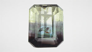 Figure 1. This 0.73 ct octagonal step cut was composed of chrysoberyl and alexandrite. The alexandrite portion showed a color change from blue-green in fluorescent light to red-purple in incandescent light. Photos by Shunsuke Nagai.