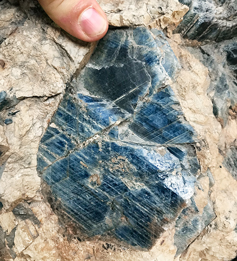 Figure 4. A large sapphire crystal in a syenitic pegmatite host rock from Pegmatite 298 in the Ilmen Mountains mineralogical reserve, Ural Mountains, Russia. Photo by Peter Lyckberg; courtesy of the Ilmen Mineralogical Museum.