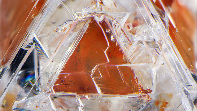 Figure 2. One of eight triangular limonitic faces in the 2.22 ct diamond crystal containing a phantom. Photomicrograph by Nathan Renfro; field of view 4.78 mm.