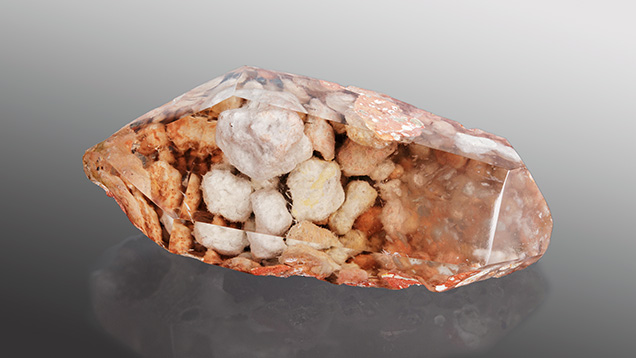 Figure 1. This 150.97 ct quartz crystal hosts pebbles of an amphibole, stacked like rocks in a stone wall. Photo by Annie Haynes.