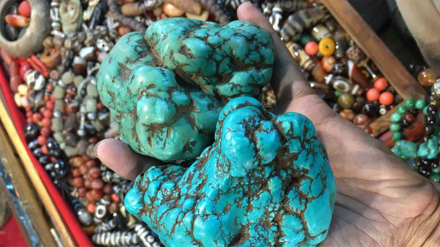 Two large pieces of old Tibetan turquoise held in the palm of a hand.