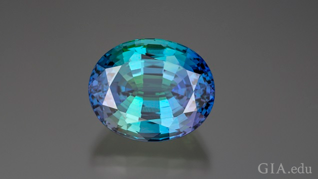 An oval shaped bicolor tanzanite has purple on each side with blue-green in the middle.