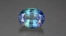 An oval shaped bicolor tanzanite has purple on each side with blue-green in the middle.