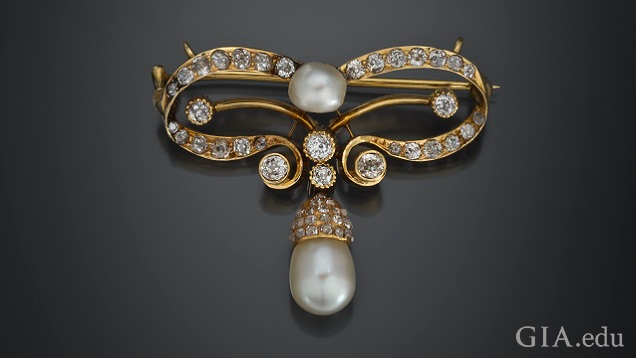 A bow forms the main brooch and a pearl pendent hangs from the bow’s center bottom.